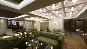 Un hall d’entrée moderne avec un canapé vert, un espace salon et un comptoir d’accueil.