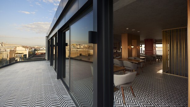Un intérieur moderne avec de grandes fenêtres, un sol à motifs et une vue sur le paysage urbain.
