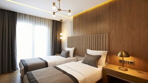 Une chambre d’hôtel avec deux lits, une table de chevet, une lampe et une vue sur l’extérieur.