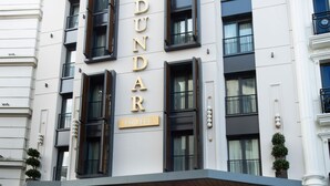 Un bâtiment d’hôtel dont la façade porte en lettres bien visibles l’inscription « DUNDAR HOTEL ».