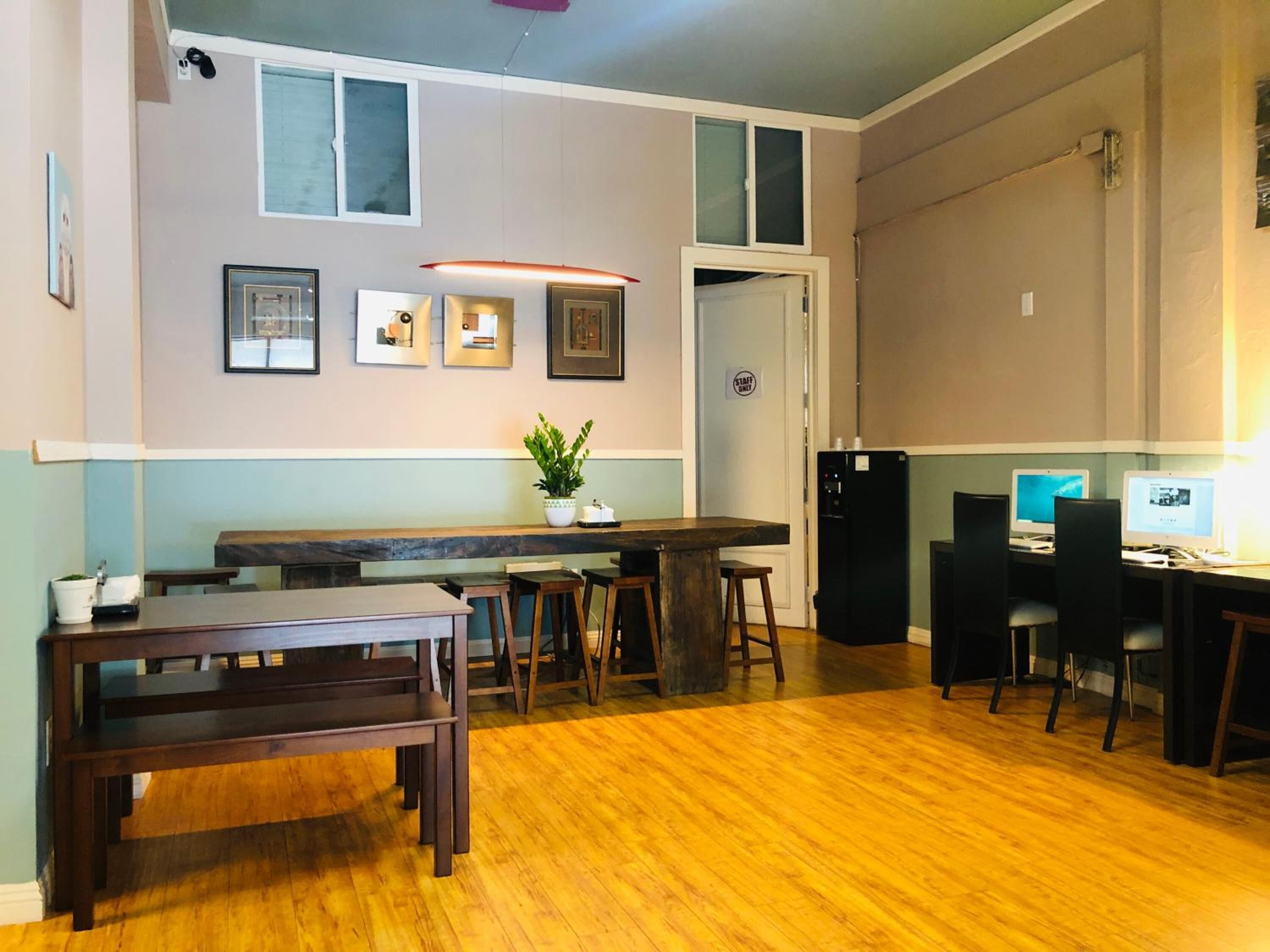 A modern kitchen with wooden flooring, a bar area, and two computers.
