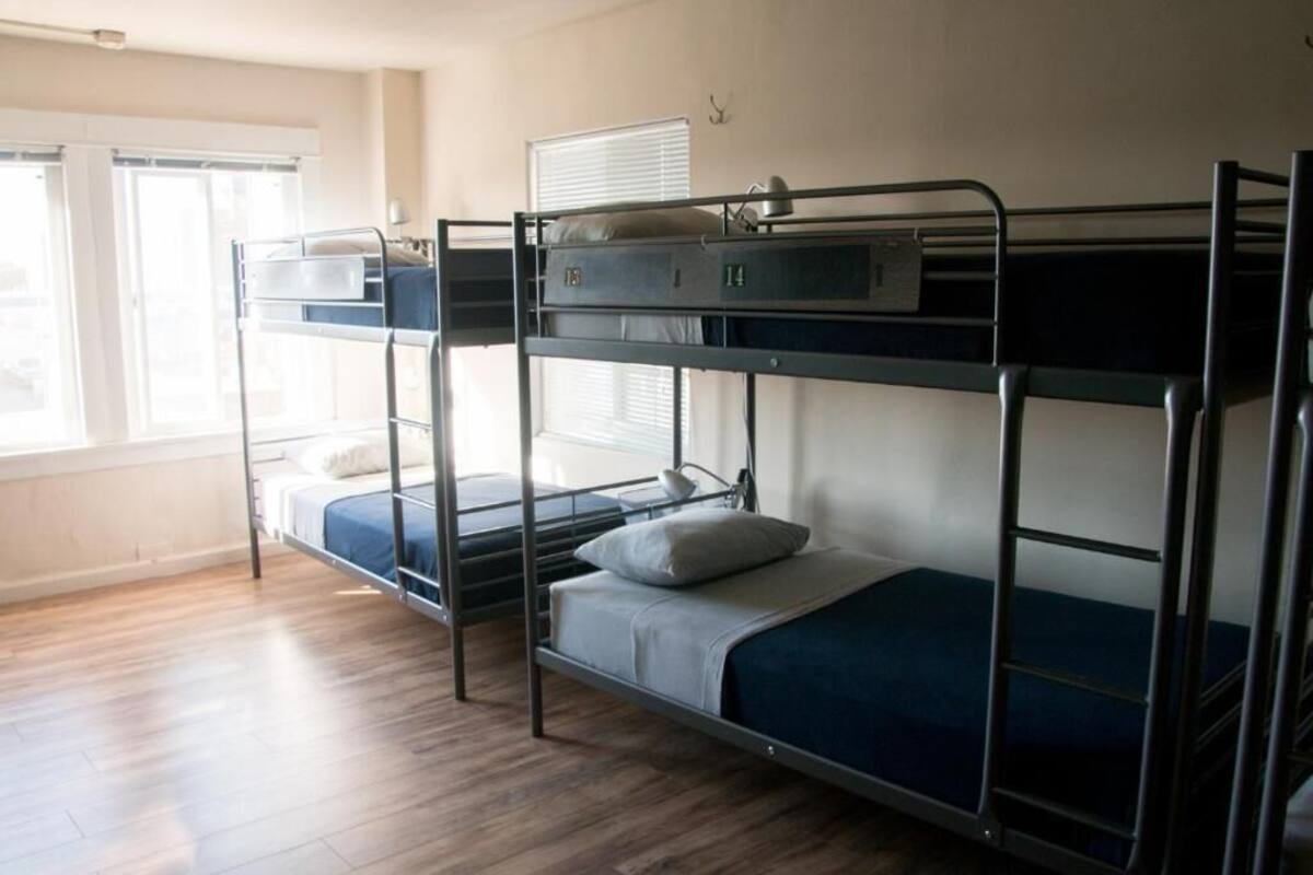 A dormitory room with bunk beds, a window, and a door.