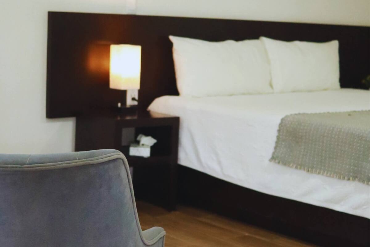 Une chambre d’hôtel avec un lit, une table de chevet, une lampe et une chaise.