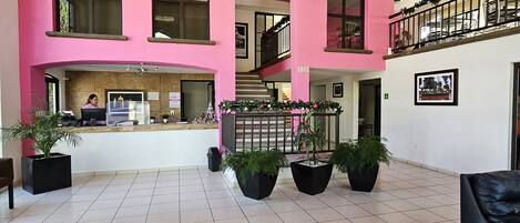 A spacious lobby with a high ceiling, large windows, and a central staircase.