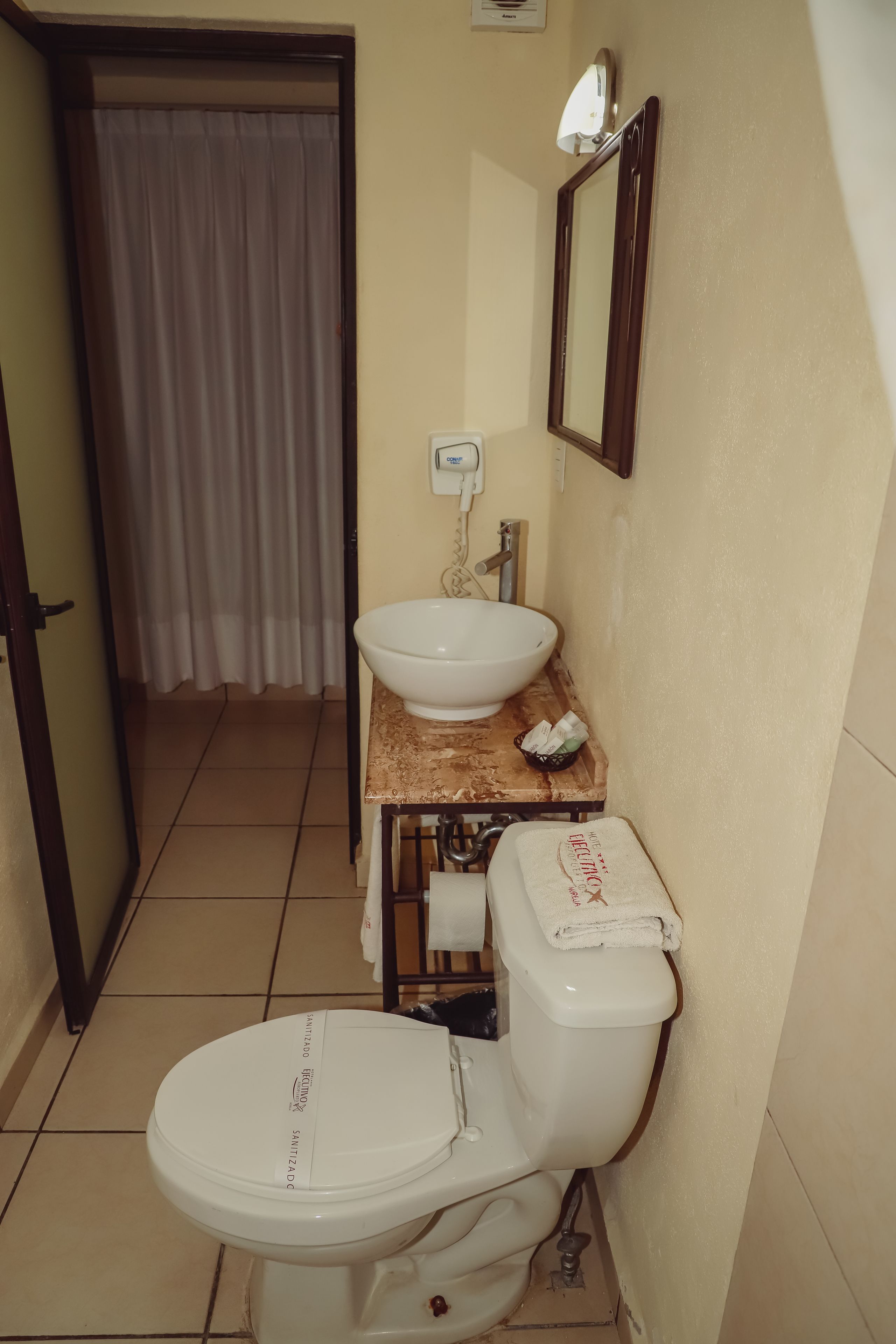 A bathroom with a toilet, sink, and mirror.
