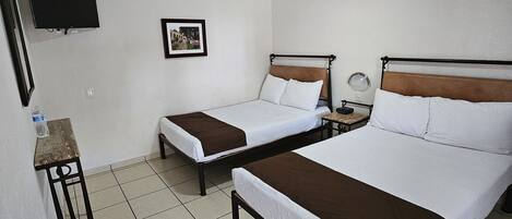 Habitación de hotel con dos camas individuales, un televisor montado en la pared, un cuadro enmarcado y una mesita con una botella de agua.