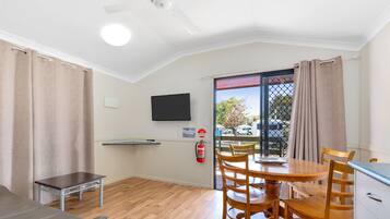 A room with a wooden dining table, chairs, a sofa, a television, and a fire extinguisher.
