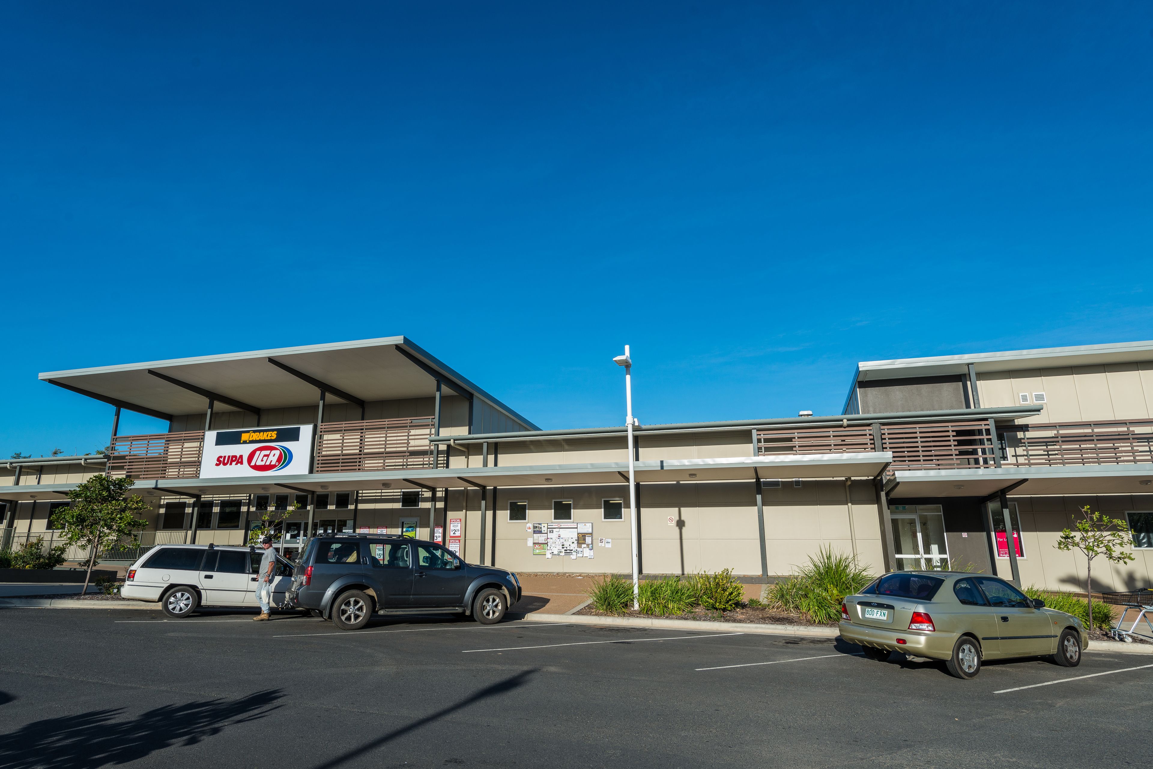 A building with a 'SUPA' sign, a parking lot, and a clear blue sky.