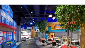 An indoor play area with a play kitchen, tables, chairs, and a playhouse. - The Reside (Houston)