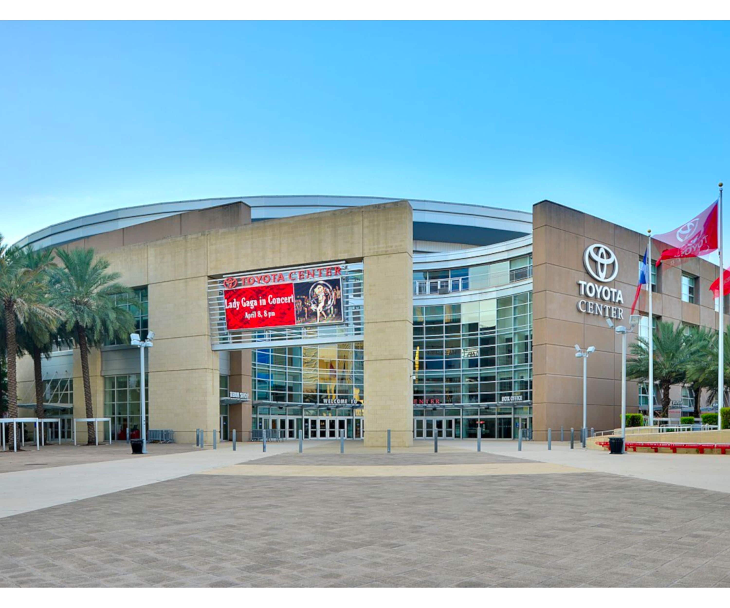A modern building with a curved facade, large glass windows, and a prominent Toyota Center sign.