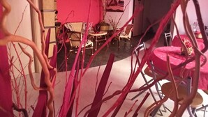 Uma sala de estar moderna com uma parede rosa, uma mesa redonda e cadeiras. Há uma escada que leva a outro andar.