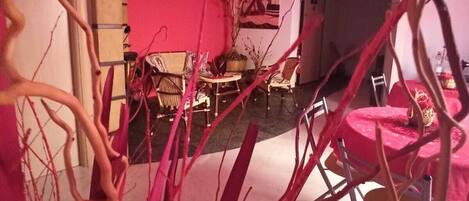 Una sala de estar moderna con una pared rosa, una mesa redonda y sillas. Hay una escalera que conduce a otro nivel.