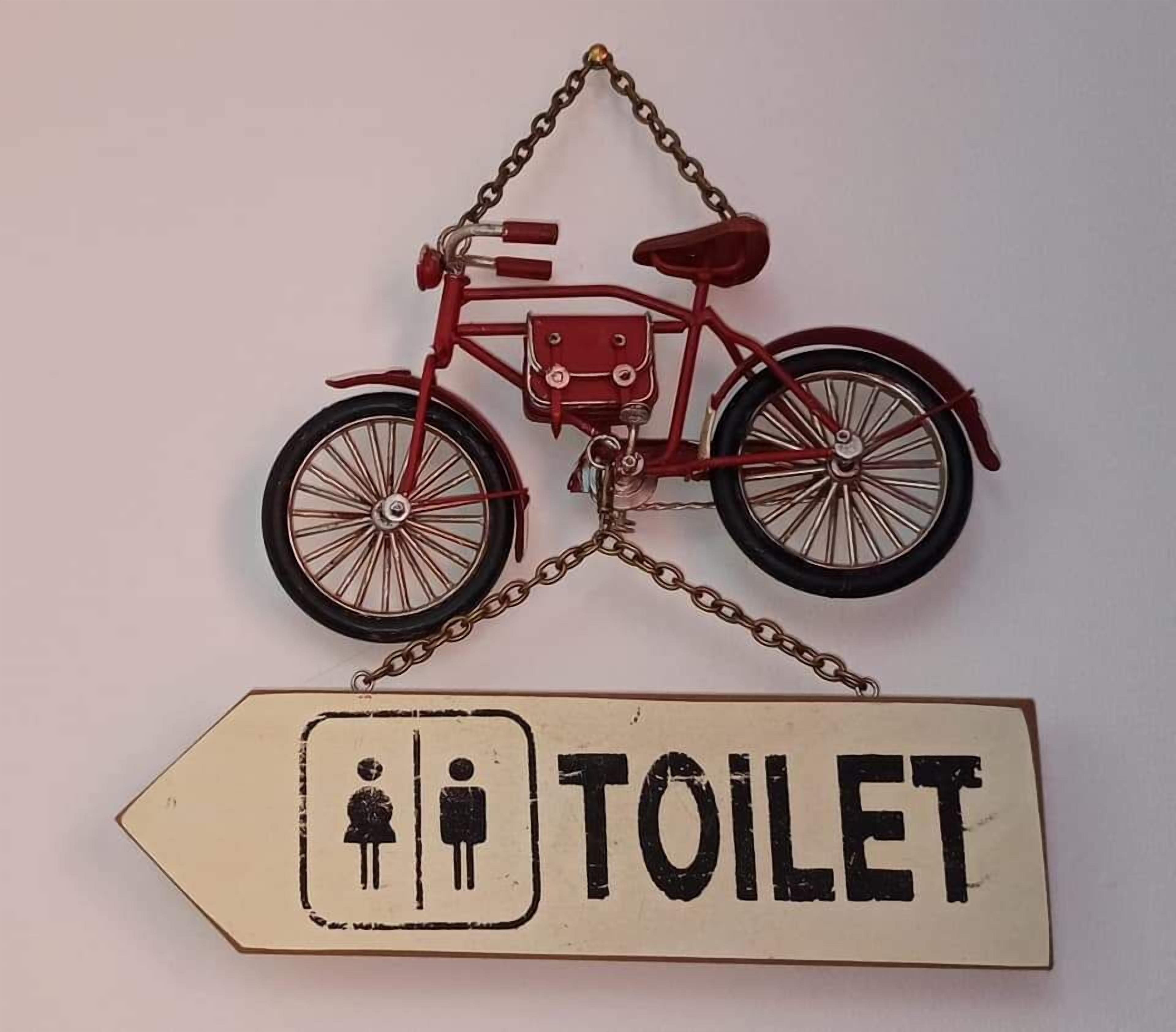 A red bicycle hanging from a chain, with a sign below it that reads "TOILET" and includes a symbol of a toilet and a person.