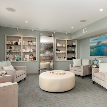 A modern living room with a round ottoman, two sofas, and built-in shelving units.