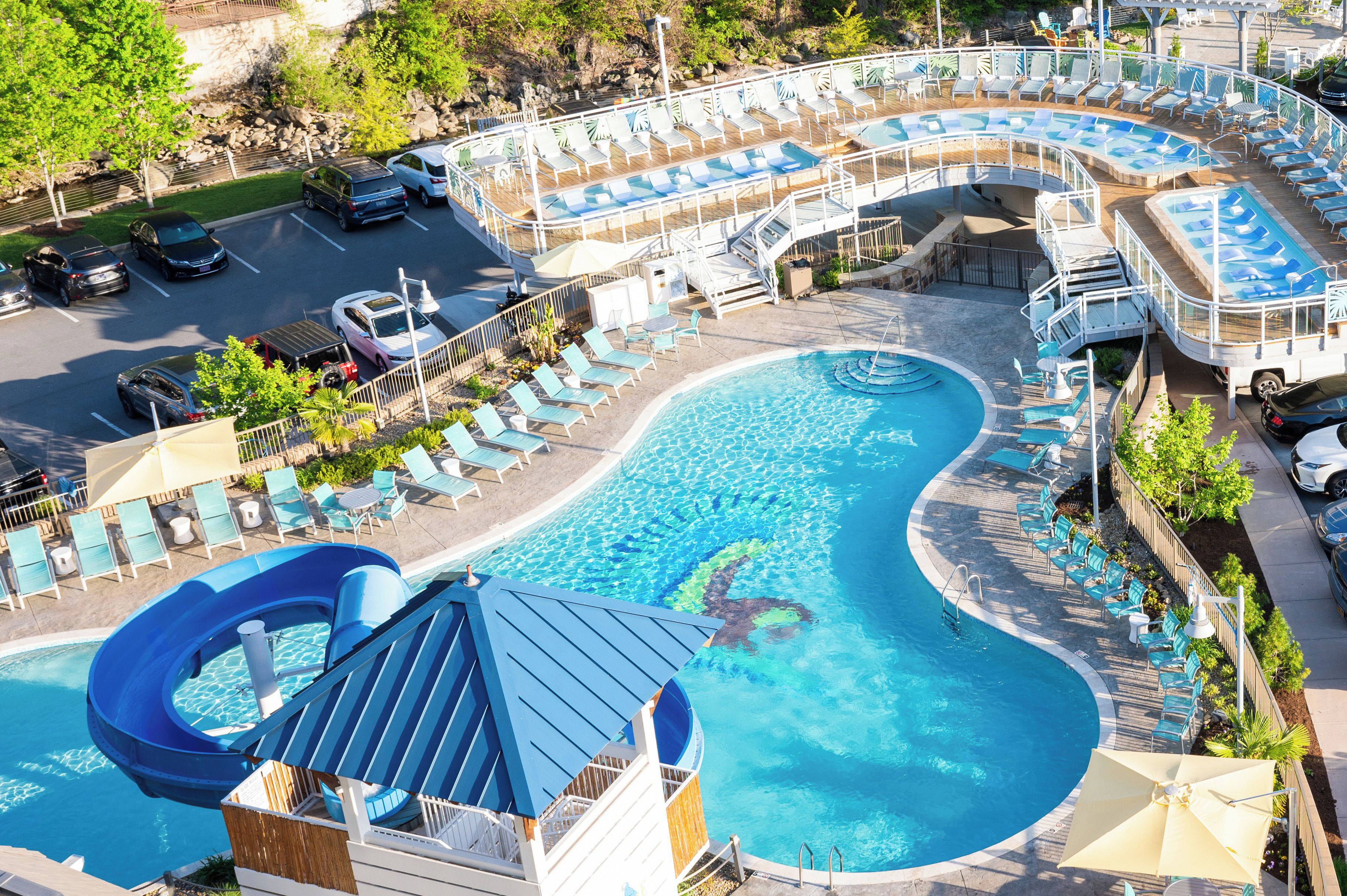 A pool area with multiple swimming pools, lounge chairs, and a water slide.