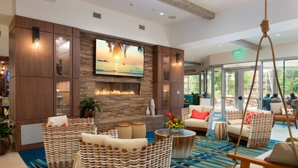 A spacious lobby with a large flat-screen TV, a fireplace, wicker furniture, and a patterned carpet. - Margaritaville Resort Gatlinburg (Gatlinburg)