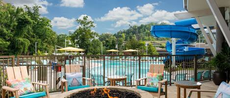 A pool area with a fire pit, lounge chairs, and a water slide.