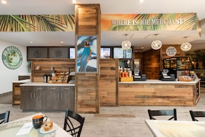 A coffee shop interior with a wooden counter, menu boards, and a tropical mural.