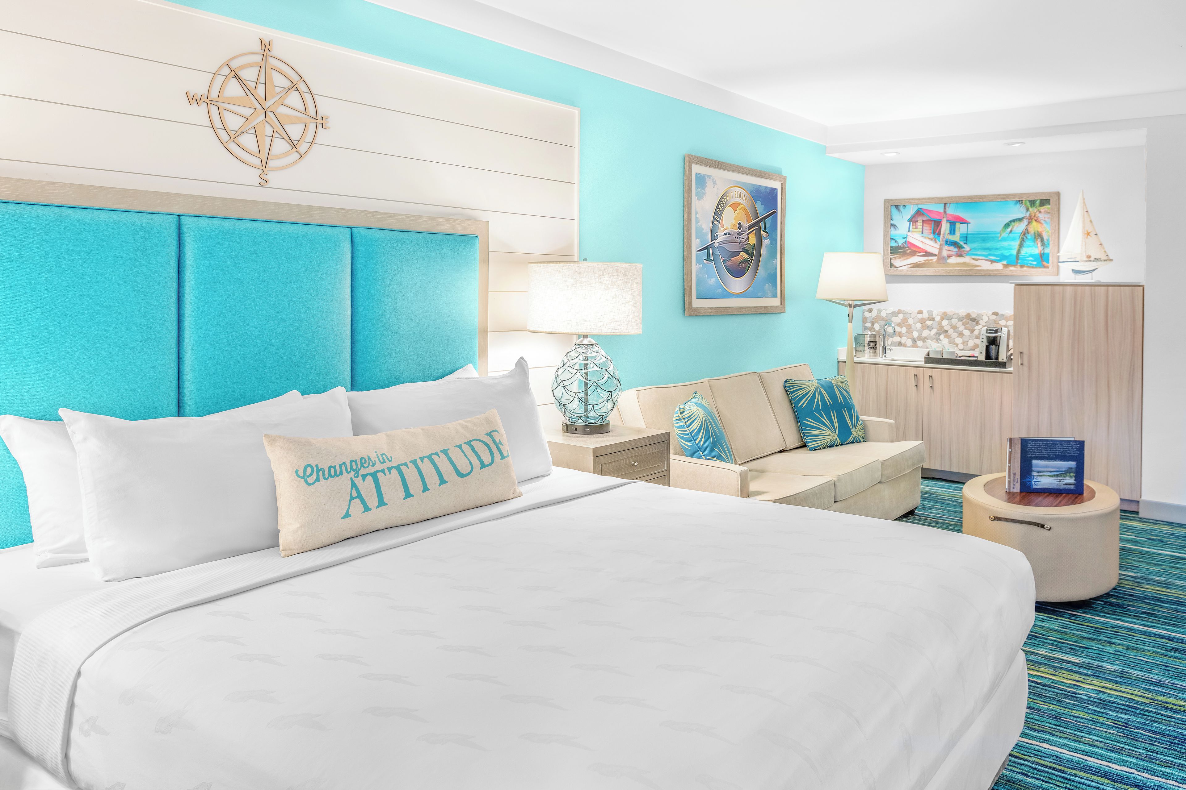 A hotel room with a large bed, a sofa, a desk, and a small table.