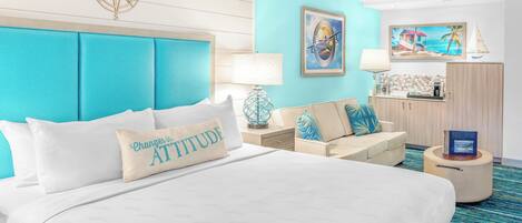 A hotel room with a large bed, a sofa, a desk, and a small table.