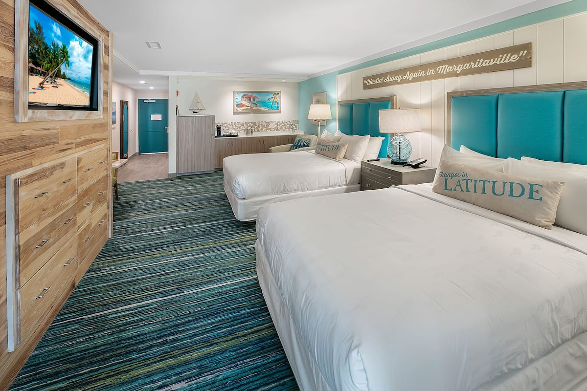 Une chambre d ’hôtel avec deux lits, une télévision, un bureau et vue sur la plage.