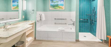 A bathroom with a bathtub, two sinks, a shower, and a toilet.