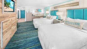 Habitación de hotel con dos camas, un aparador de madera, un baño y vistas a la playa.