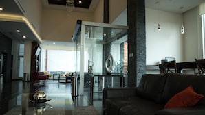A modern living room with a glass partition, leather sofa, and a coffee table. - Lithio Hotel (Veracruz)