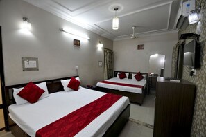A hotel room with two beds, a desk, a mirror, and a television. - Hotel New SS Residency (Amritsar)
