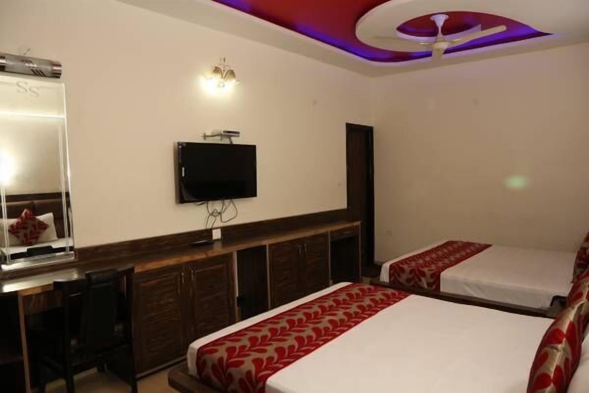 Una habitación de hotel con cama, escritorio, televisión y lámpara en el techo.