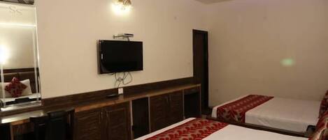 Una habitación de hotel con cama, escritorio, televisión y lámpara en el techo.