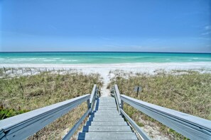 A wooden staircase leading to a beach with clear turquoise water.