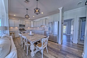 A spacious kitchen with white cabinetry, a large island, and modern appliances.