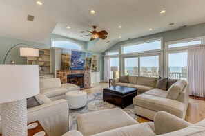 Relax in this ocean-view living room with a fireplace, sofa, and ceiling fan.