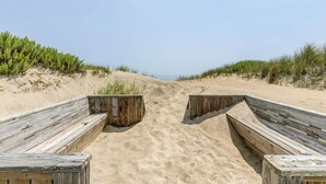 A sandy beach with wooden walkways leading to the water. - Pebble Beach | Oceanfront | Dog Friendly, Private Pool, Hot Tub | Nags Head (Nags Head)