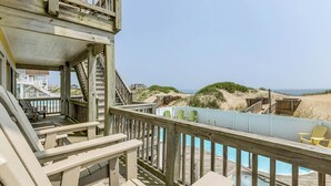 A wooden deck with a pool, chairs, and a view of the beach. - Pebble Beach | Oceanfront | Dog Friendly, Private Pool, Hot Tub | Nags Head (Nags Head)