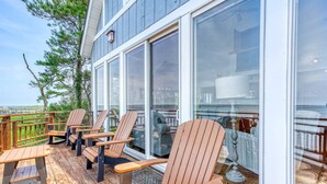 En træterrasse med Adirondack-stole og en glasdør, der fører ind til et rum.