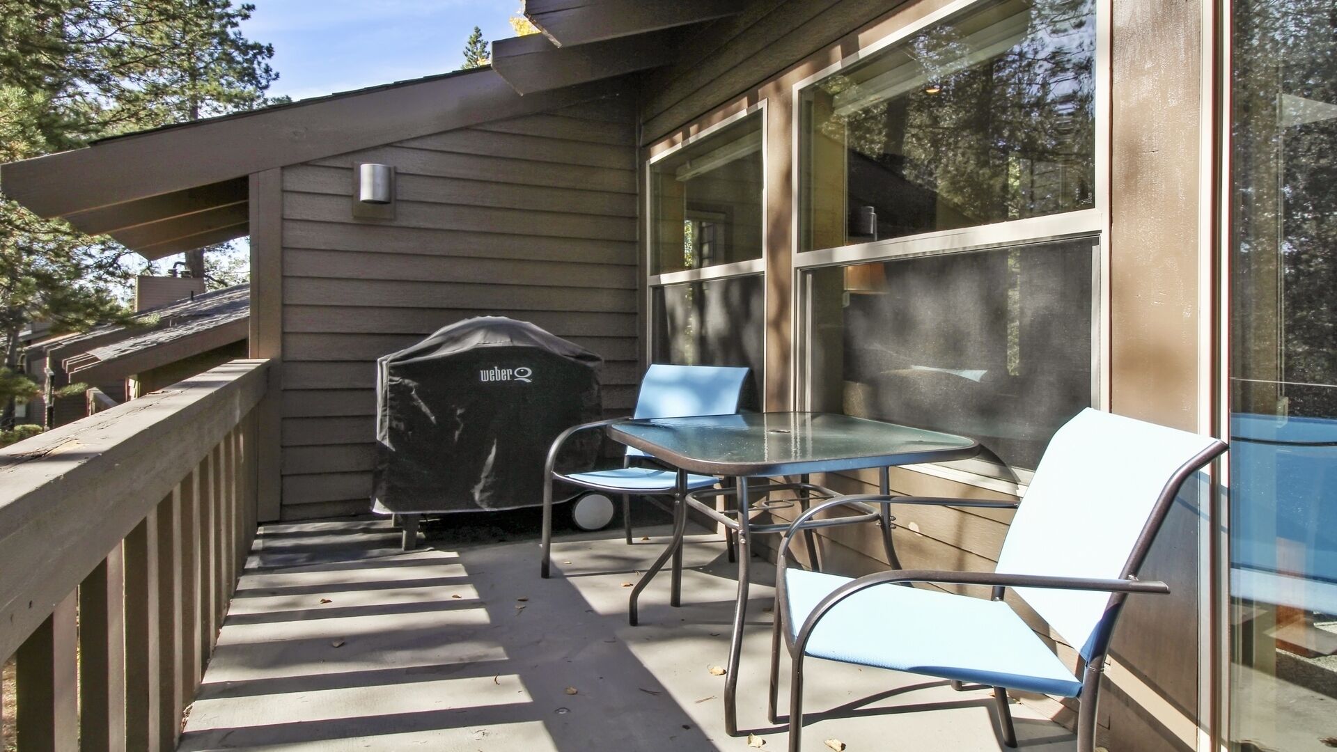 A covered patio with a grill, a table, and two chairs.