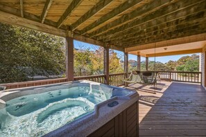 Una vasca idromassaggio su un pontile di legno con vista su alberi e case.