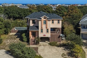A two-story house with a front deck, a garage, and a driveway. - A Corolla Corral | Sound Side | Private Pool, Hot Tub | Corolla (Corolla)