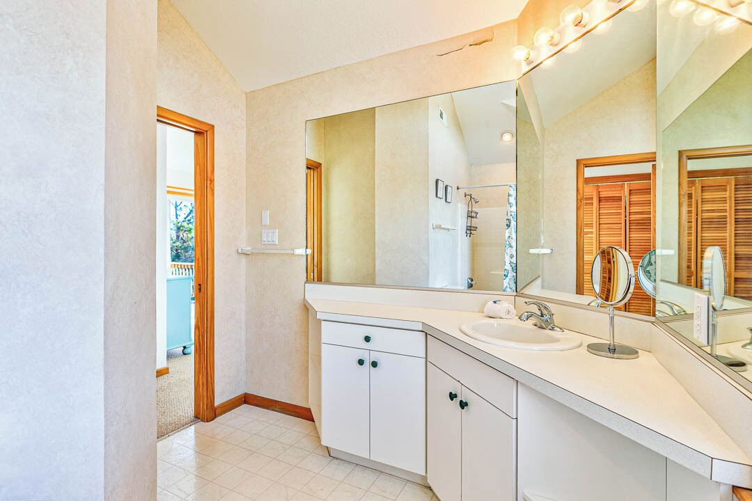 Un baño moderno con un espejo grande, muebles blancos y un lavamanos.