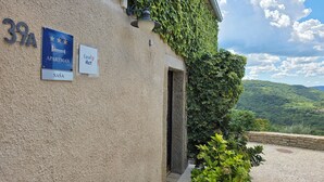 A building with a sign indicating it is an apartment, a local host sign, and a view of a lush green landscape. - Family-friendly house in Draguć, Istria, with gorgeous garden and stunning view (Cerovlje)
