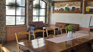 A rustic dining area with a large wooden table, stone flooring, and exposed wooden beams. - Family-friendly house in Draguć, Istria, with gorgeous garden and stunning view (Cerovlje)