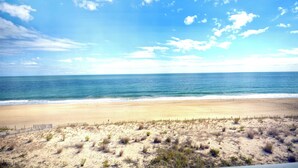 Ein Strand mit sandigem Ufer und einem Holzzaun im Vordergrund.