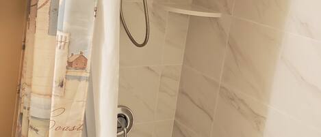 Un baño con bañera, ducha y cortina decorada con motivos playeros.