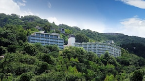 Un hotel de varios pisos, rodeado de exuberante vegetación y colinas.
