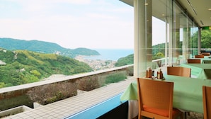 Un restaurante con vistas a un pueblo costero y colinas.
