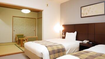 A hotel room with two beds, a chair, a bedside table with a phone, and a wall-mounted light.