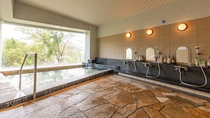 Un baño moderno con piso de piedra, un ventanal amplio y varios lavamanos con espejos y dispensadores de jabón.