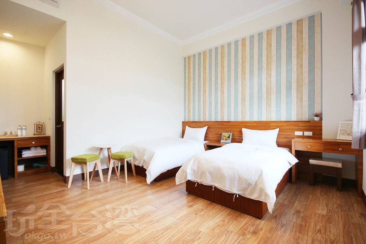 A hotel room with two beds, a desk, a chair, and a small table.